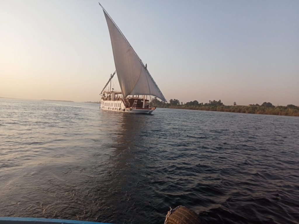 Traditional dahabiya sailing on the Nile with raised sail during late afternoon light