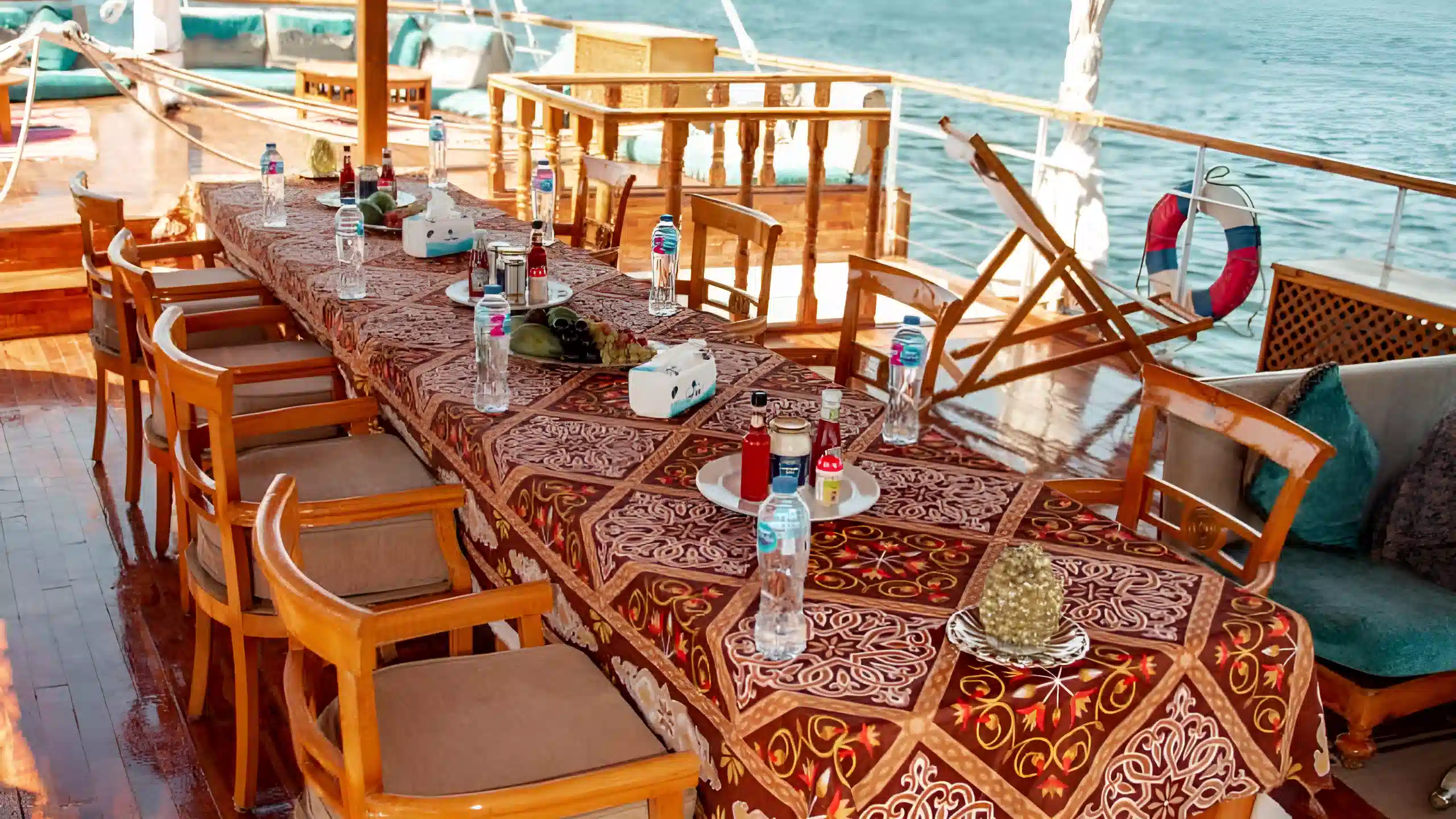 Outdoor dining table on a traditional dahabiya boat with Nile River view and oriental tablecloth