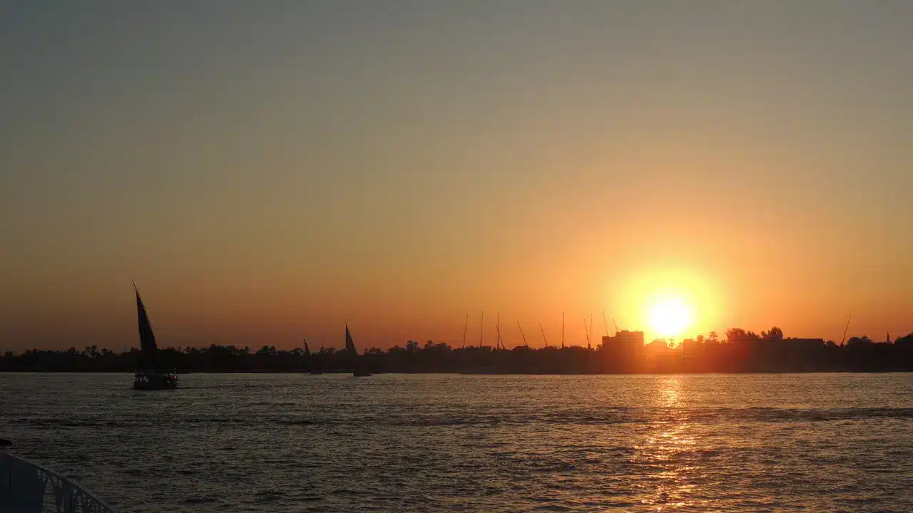 Sunset over the Nile River with silhouettes of feluccas sailing