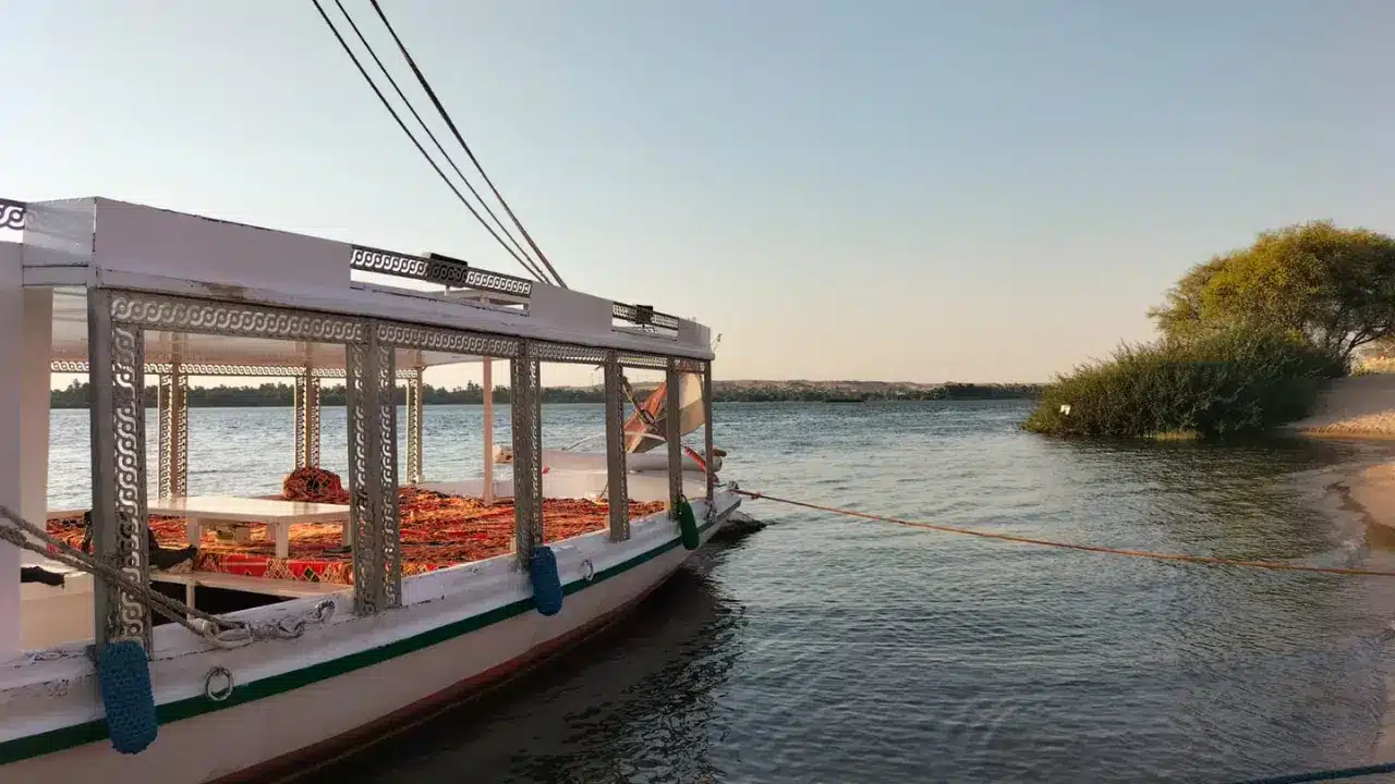 Traditional felucca boat docked by the Nile Riverbank at sunset.