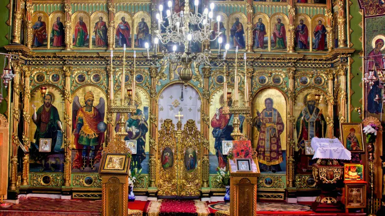 Golden Orthodox iconostasis with sacred icons and chandeliers