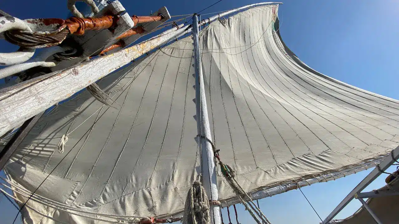 Feluccas and a dahabiya boat sailing on the Nile River near Luxor with desert mountains in the background