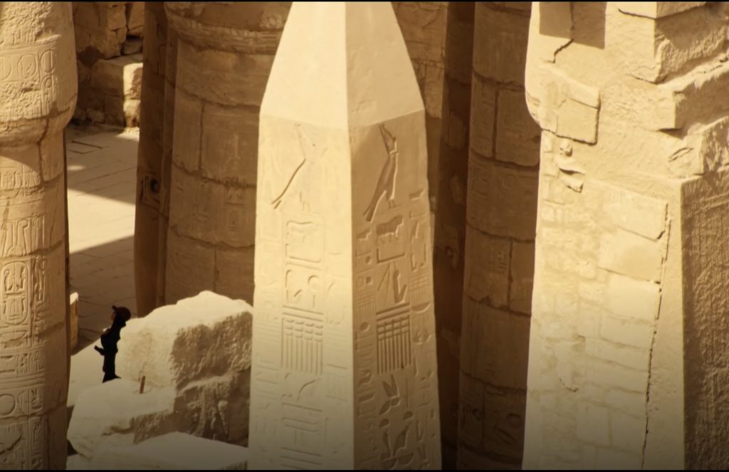 Ancient Egyptian obelisk surrounded by stone columns inside Karnak Temple complex in Luxor Egypt
