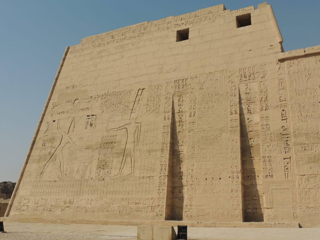 Ancient relief carvings on the exterior wall of Kom Ombo Temple in Egypt showing pharaoh and hieroglyph inscriptions