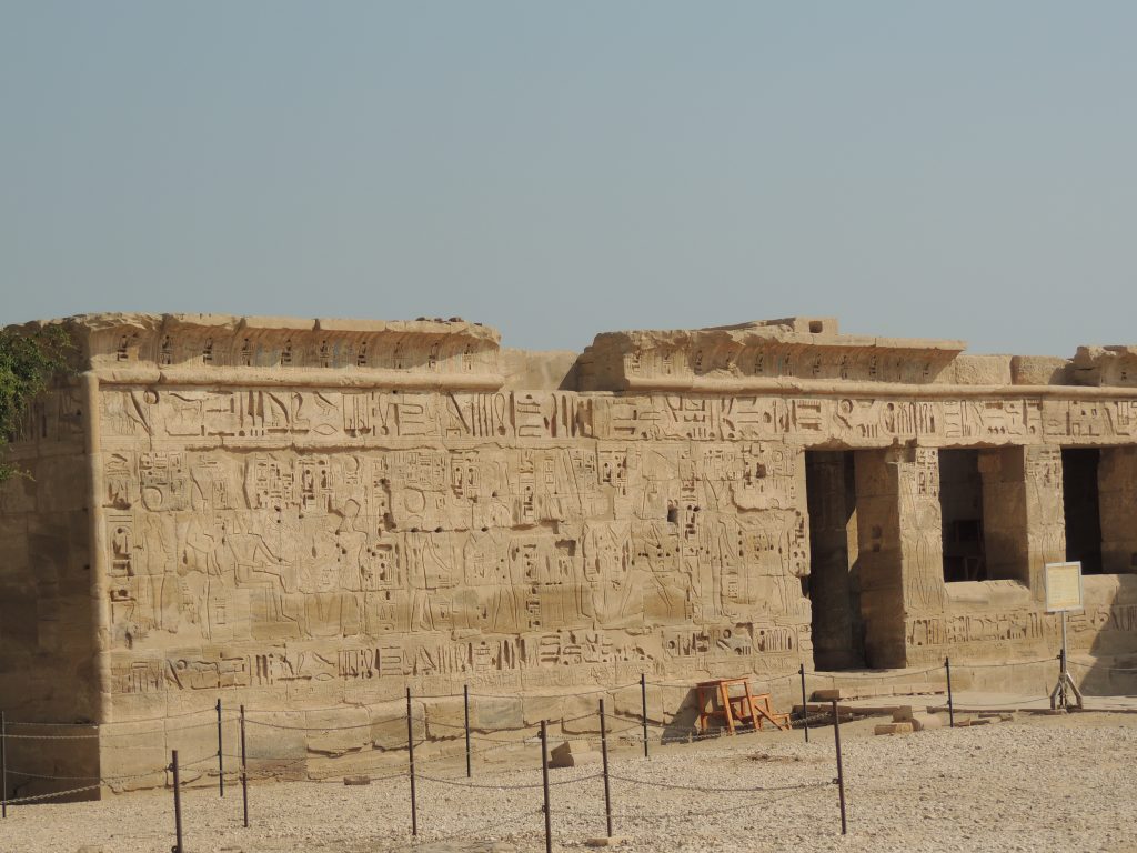 Ancient stone wall with hieroglyph reliefs and doorway at Kom Ombo Temple in Egypt