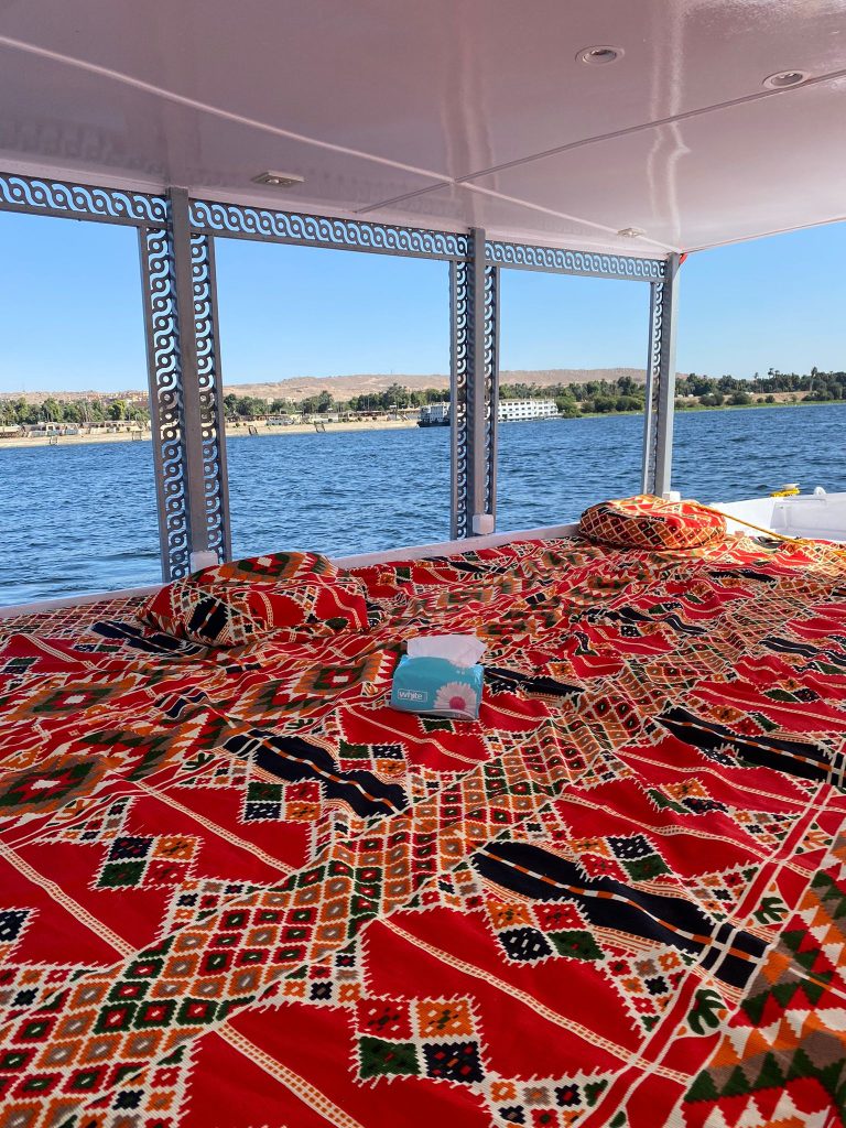Traditional carpet seating area on the covered deck of the felucca Maitea overlooking the Nile near Aswan Egypt