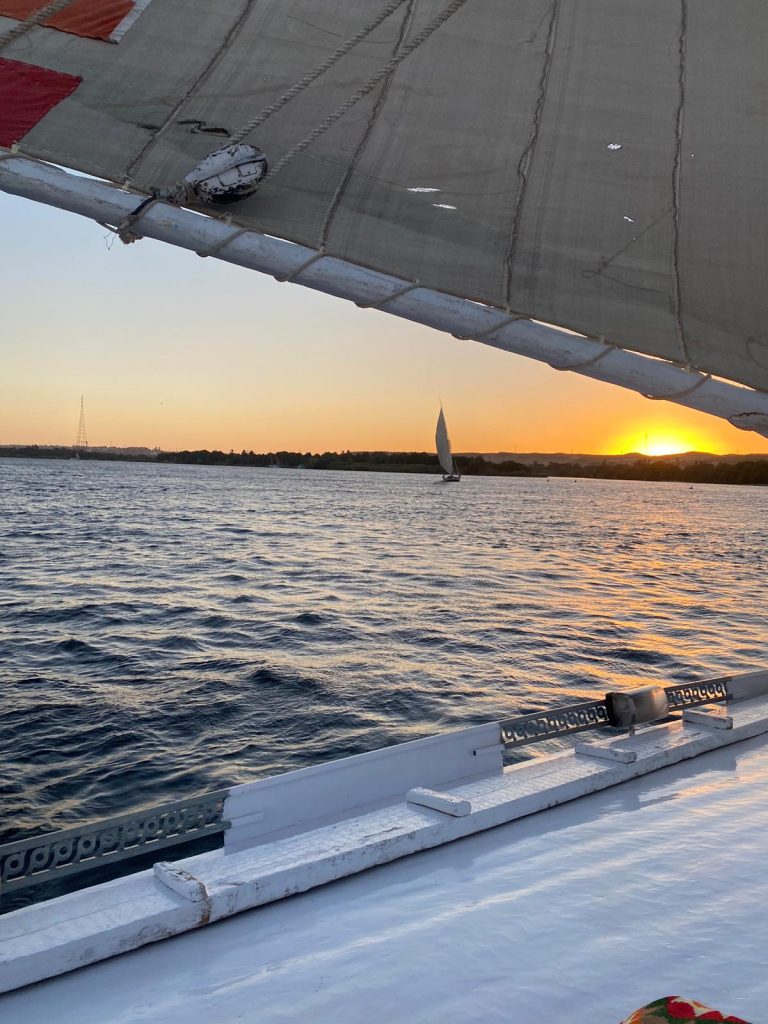 Traditional felucca sailing on the Nile at sunset near Aswan Egypt seen from another felucca deck