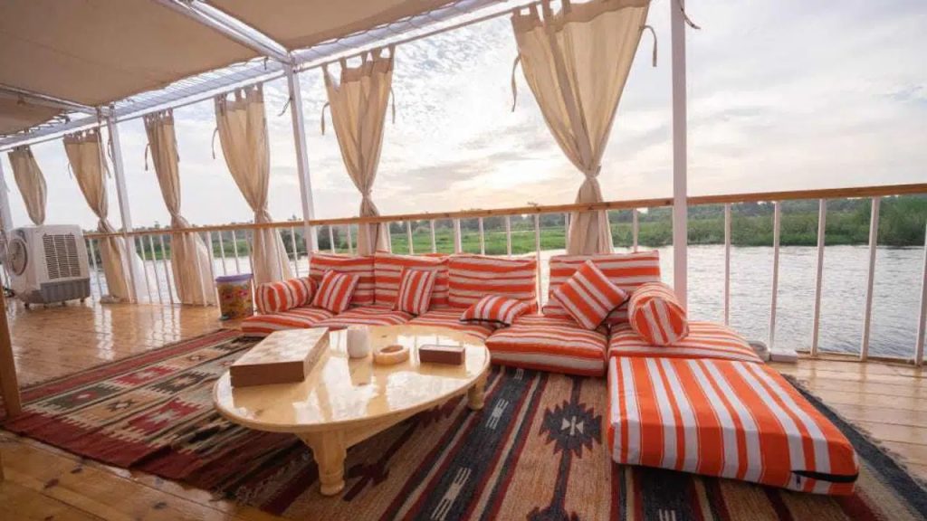 Open deck lounge area on Nunet dahabiya with cushions and Nile river view in Egypt