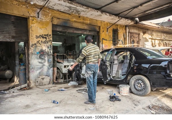 Egyptian mechanic repairing a car in a traditional Cairo workshop